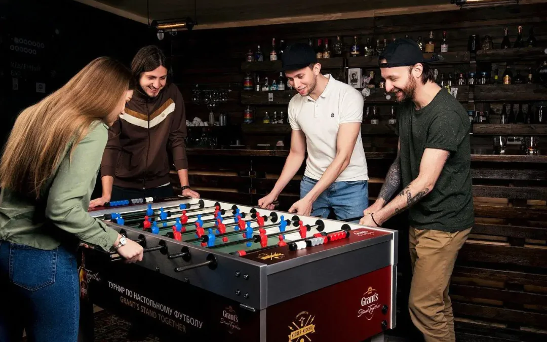 Personas jugando al futbolín en un bar.