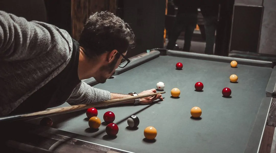 Hombre jugando billar en mesa oscura