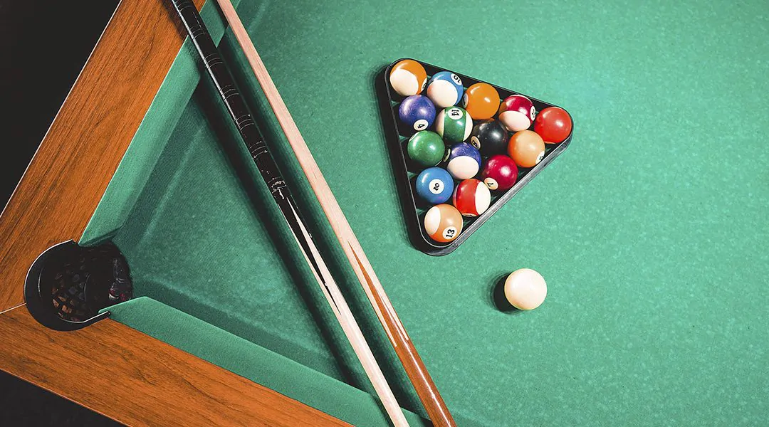 Mesa de billar con bolas y tacos.