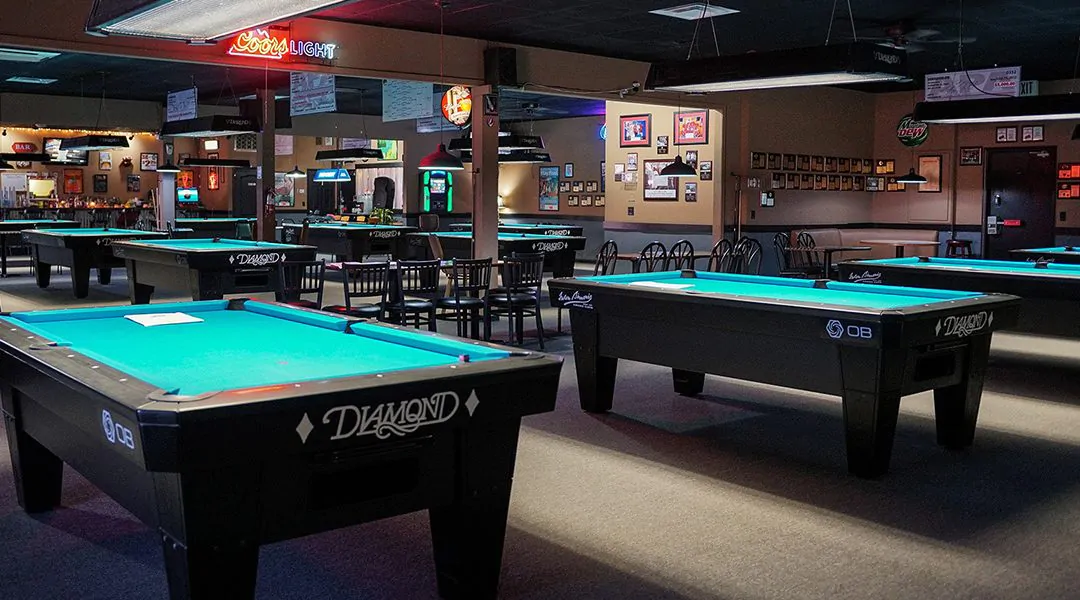 Sala de billar con mesas iluminadas y sillas