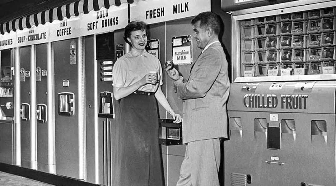 Pareja frente a máquinas expendedoras vintage.