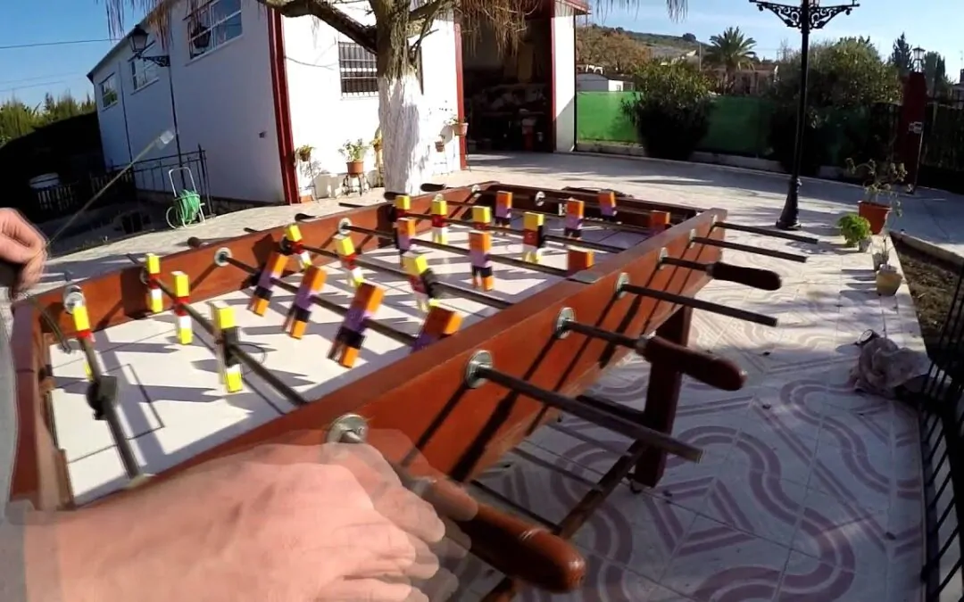Mesa de futbolín en un patio exterior soleado.