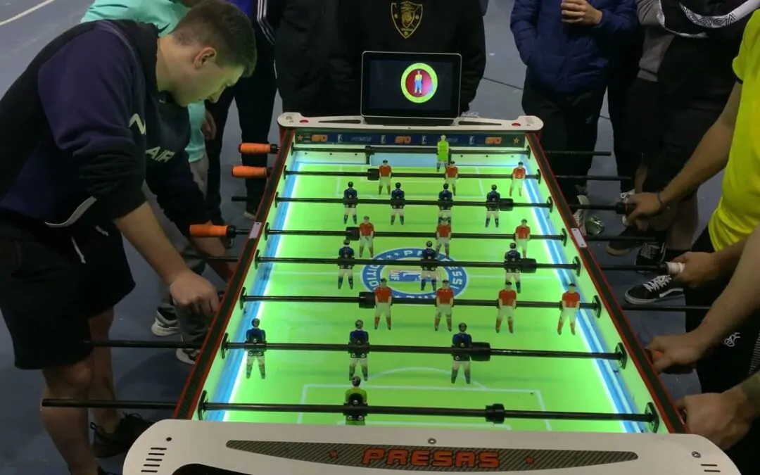 Personas jugando al futbolín iluminado