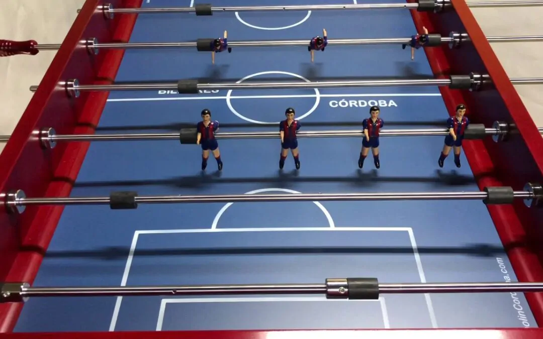 Mesa de futbolín con figuras en camisetas oscuras.