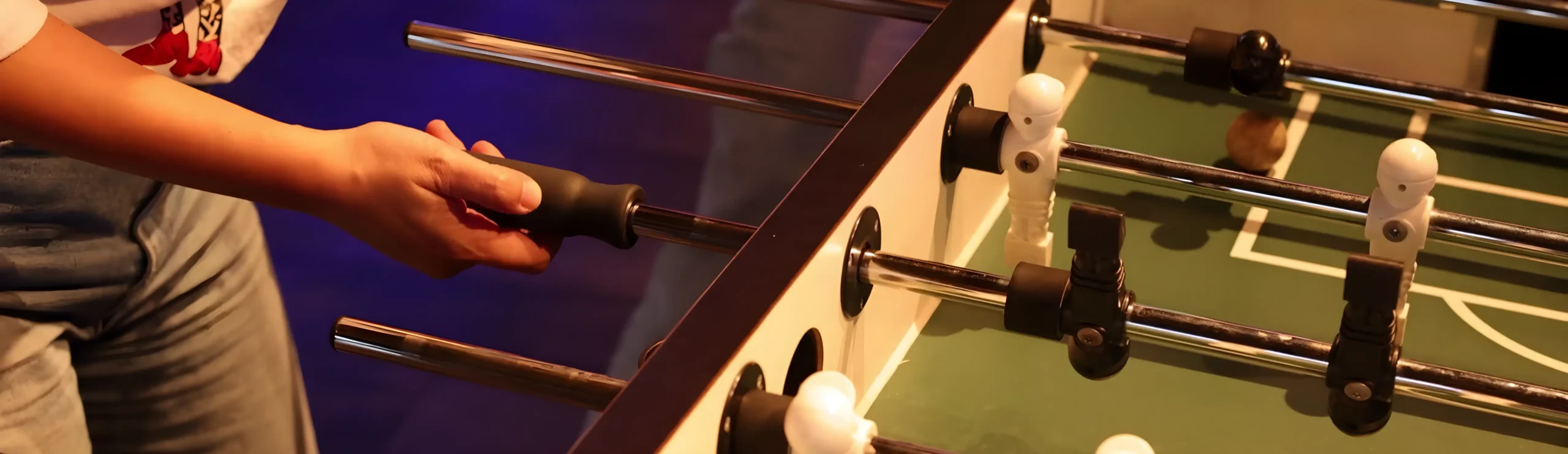 Persona jugando futbolín en mesa de fútbol.