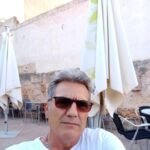 Hombre con gafas de sol en terraza exterior.