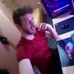 Persona sonriendo en habitación con computadora.