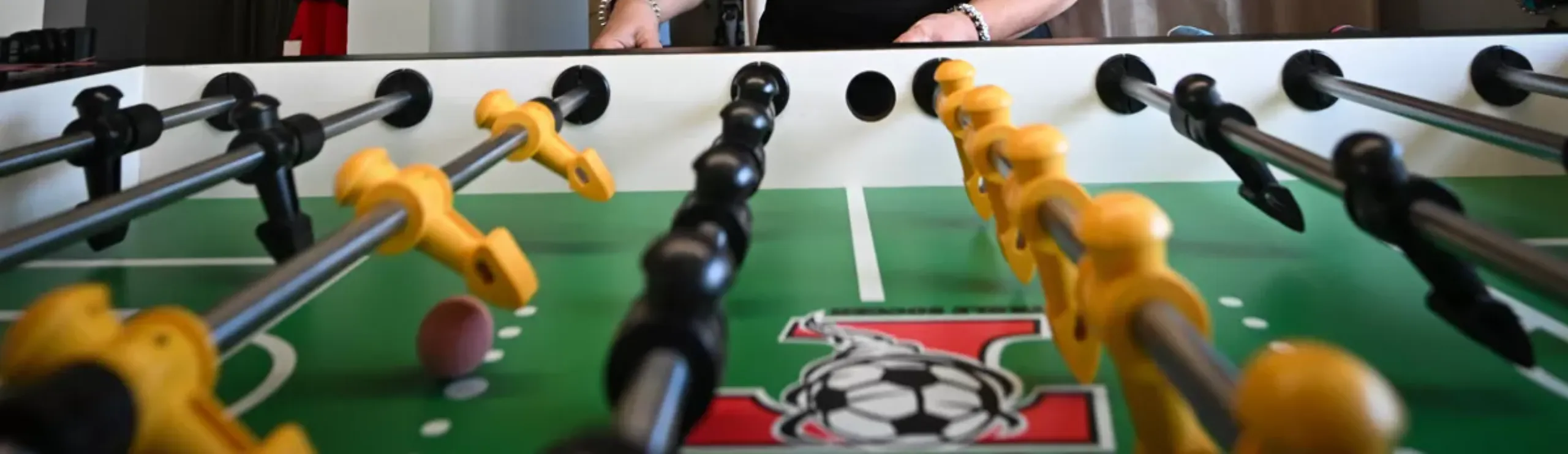 Alquiler de futbolines en Cáceres Partida de futbolín en progreso, manos visibles.