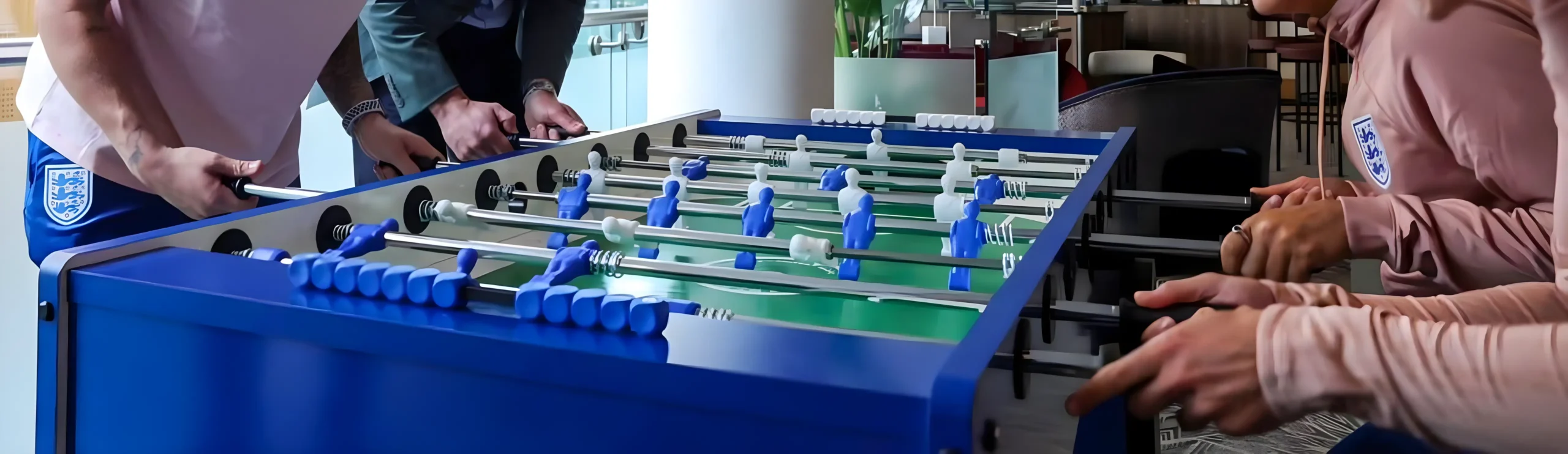 Alquiler de futbolines en La Rioja Personas jugando futbolín en una oficina moderna.