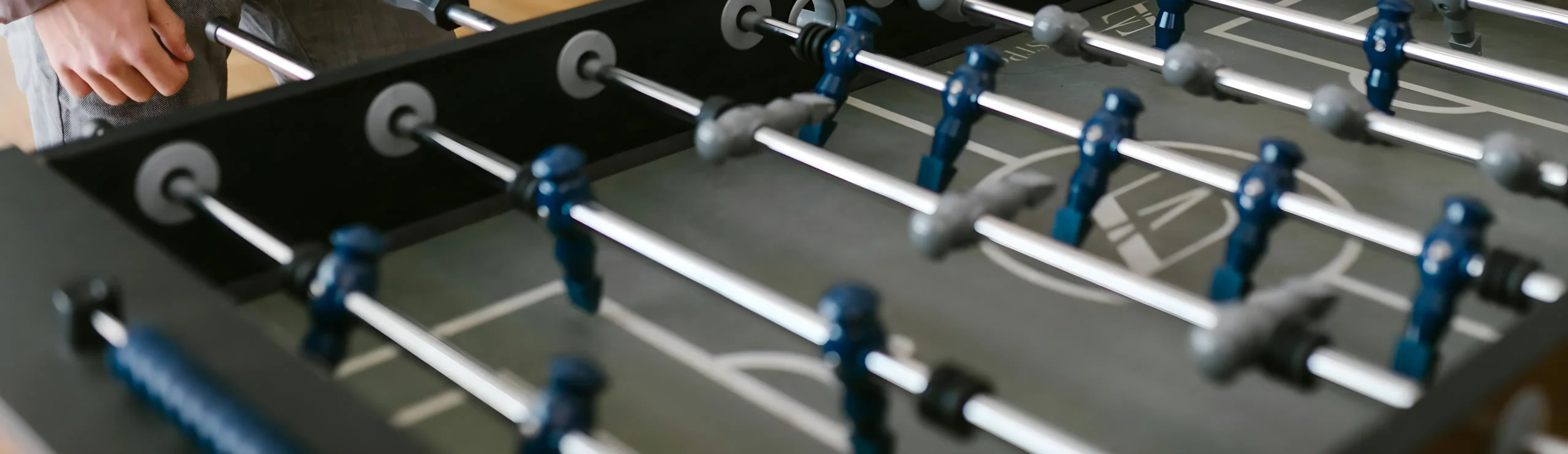 Jugador en mesa de futbolín en partido amistoso.