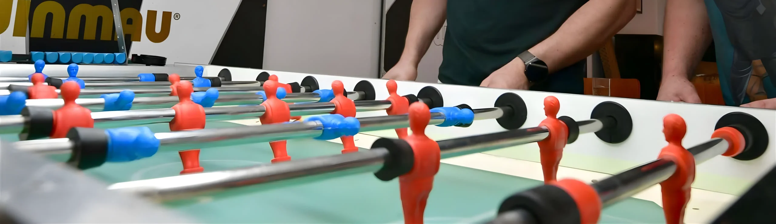 Alquiler de futbolines en Pontevedra Personas jugando al futbolín en un salón.